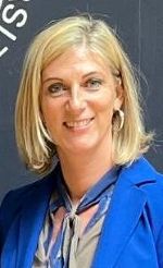 Porträt einer Person mit blonden Haaren und blauem Sakko. Die Person lächelt freundlich.